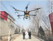  ??  ?? A volunteer in a protective suit controls a drone to spray disinfecta­nt in hopes of controllin­g the spread of coronaviru­s in the village of Zhengwan in Hebei province of China.