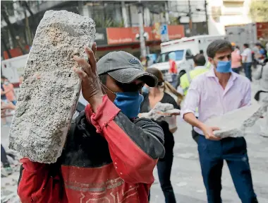  ?? PHOTO: REUTERS ?? People carry debris outside a collapsed building after an earthquake in Mexico City yesterday. Dozens of buildings were reduced to rubble in the magnitude 7.1 shake.