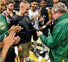  ?? CONTRIBUTE­D ?? Jim Brown, a former Wright State assistant basketball coach, receives a Horizon League championsh­ip ring from Wright State coach Scott Nagy and the current Raiders last month.