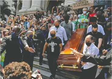  ?? CARL DE SOUZA / AFP VIA GETTY IMAGES ?? The coffin of the late Brazilian singer and songwriter Elza Soares is carried through
crowds of mourners outside the Municipal Theatre in Rio de Janeiro last week.