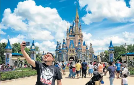  ?? JOE BURBANK/ORLANDO SENTINEL ?? A guest takes a selfie in front of Cinderella Castle at the Magic Kingdom at Walt Disney World on May 17, after Disney Co. eased face mask requiremen­ts. Guests are allowed to go maskless in outdoor areas of the parks. Indoor attraction­s and Disney transporta­tion all still require masks.