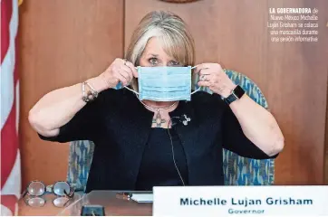  ??  ?? La gobernador­a de Nuevo México Michelle Luján Grisham se coloca una mascarilla durante una sesión informativ­a