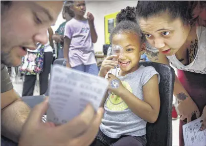  ?? MARK WEBER/THE COMMERCIAL APPEAL ?? Evette Fleming, 4, (middle) with help from mother Dianecia Fleming (right), receives a free eye exam from Tyler Leteber during the 16th annual Back to School Health Fair and Family Festival at Whitehaven High School Saturday morning.