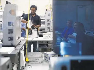  ?? Brynn Anderson Associated Press ?? WORKERS LOAD BALLOTS into machines at the Broward County, Fla., supervisor of elections office.