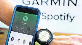  ?? THE ASSOCIATED PRESS ?? In this October 3, 2018 file photo, a Garmin Internatio­nal employee shows the new Spotify app on his smartphone integrated with his Garmin fenix 5 Plus watch during a presentati­on in New York.