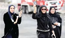  ??  ?? Kuwaiti women flash their passports as they arrive to cast their votes at a polling station.