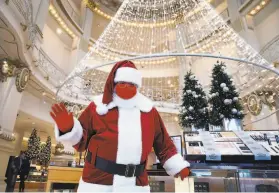  ?? Paul Chinn / The Chronicle ?? Santa Claus, or Christophe­r MacGowan in real life, greets customers arriving at Neiman Marcus in San Francisco. Christmas shopping is a bit muted in 2020.