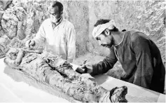  ??  ?? Egyptian archaeolog­ical technician­s restore a mummy wrapped in linen. — AFP photo