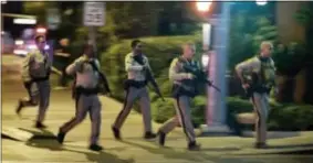  ?? ASSOCIATED PRESS ?? Police run to cover at the scene of a shooting near the Mandalay Bay resort and casino on the Las Vegas Strip, Sunday in Las Vegas.