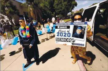  ?? GENARO MOLINA — LA TIMES/POLARIS ?? Venice High School graduate Kensei Ono, 18, waits for his turn to be photograph­ed while his mother Susie holds a placard featuring her son while taking part in the Venice High School Class of 2020 Senior Graduation Parade in Venice in June 2020.