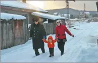  ??  ?? Zhao, Gu and their daughter walk down a snow-covered lane on their way home.