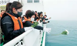 ?? Yonhap ?? A bereaved family member tosses a flower during a memorial service held near Donggeocha­do in Jindo County, South Jeolla Province, Tuesday, in memory of victims who died 10 years prior on a ferry that sank on its way to Jeju Island on April 16, 2014.