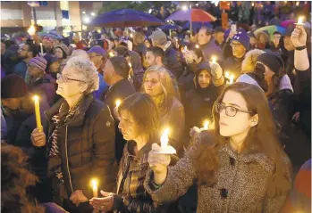  ?? MATT ROURKE/AP ?? People hold candles as they gather for a vigil in the aftermath of a deadly shooting at the Tree of Life Congregati­on.