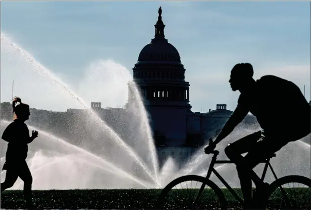  ?? — AP ?? The Capitol is seen as water sprinklers soak the National Mall on a hot summer morning in Washington, on July 15, 2022. A new poll finds that most Americans share many core values on what it means to be an American despite the country’s deep political polarizati­on.