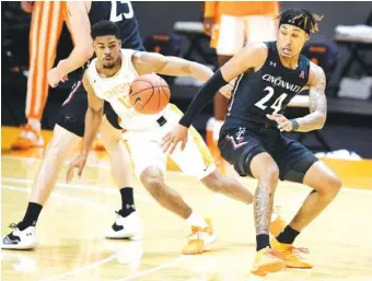  ?? AP PHOTO BY CALVIN MATTHEIS ?? Cincinnati guard Jeremiah Davenport (24) loses control of the ball as Tennessee’s Victor Bailey Jr. goes after it during the first half of Saturday’s game in Knoxville. Tennessee won 65-56 to improve to 2-0.