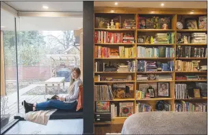  ?? (NWA Democrat-Gazette/J.T. Wampler) ?? April Wallace in her favorite space in her home earlier this month. The new primary bedroom houses her collection of books in a wall of built-in bookshelve­s that her father made.