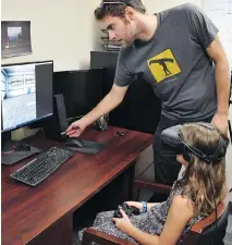  ?? UNIVERSITY OF GUELPH ?? Andrew Vierich, a University of Guelph software developer, looks on as Ruby Corbett learns how to safely cross streets using a virtual reality program that Vierich helped create.