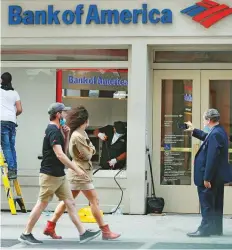  ?? AP ?? Pedestrian­s walk past a Bank of America branch in Lower Manhattan, New York. BofA’s acquisitio­n of shares in Emirates NBD is likely done through market deals, sources say.