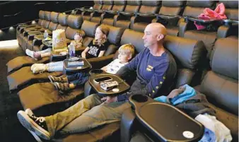  ?? SANDY HUFFAKER PHOTOS ?? Jason Mahrdt watches a movie with his children Ryan, 4, Phoebe, 8, and Olivia, 4, at Angelika Film Center at Carmel Mountain Plaza on Saturday, a day after the theaters in San Diego reopened.