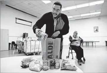  ?? JOSE M. OSORIO/CHICAGO TRIBUNE PHOTOS ?? Arthur Marbly shows some of the food at a pantry his father, Corwin Marbly, right, runs out of St. Matthew UM Church.