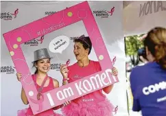  ??  ?? Two women, in pink attire typical at the Susan G. Komen Race for the Cure, get a keepsake photo after finishing the fundraisin­g event.