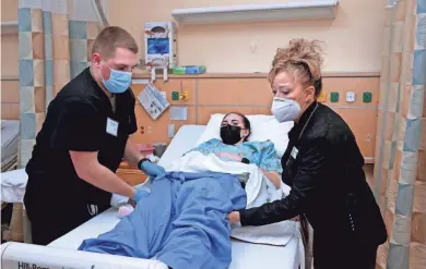  ?? ANGELA PETERSON / MILWAUKEE JOURNAL SENTINEL ?? Wisconsin National Guard 2nd Lt. Christophe­r Kuechenmei­ster, left, is given instructio­n on patient dressing from instructor Debbie Wilson, right, at Madison College on on Wednesday while Spc. Kasey Carter takes the role of patient.