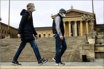  ?? MATT ROURKE - THE ASSOCIATED PRESS ?? A couple in protective masks during the coronaviru­s outbreak walk past the Philadelph­ia Museum of Art in Philadelph­ia, Friday, April 3. The museum has temporaril­y closed due to the COVID-19 pandemic.