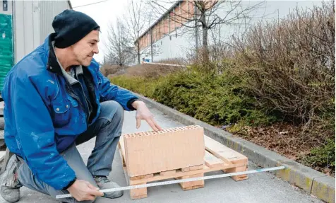  ??  ?? Edgar Hass zeigt mit dem Meterstab, wie weit die Paletten in den Gehweg hineinragt­en. Sein Chef hatte einen Bescheid vom Tiefbauamt bekommen.