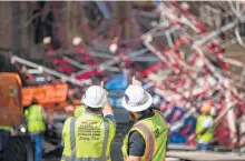  ??  ?? Workers decide their next move at the site of the collapse. The scaffoldin­g was torn from an office building owned by AT&T by winds gusting up to 60 mph.