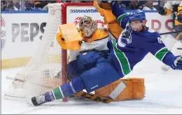  ?? Vancouver Canucks’ Dakota Joshua, front, crashes into Nashville Predators goalie Juuse Saros during the third period in Game 2 in Vancouver on Tuesday. ?? THE CANADIAN PRESS