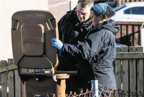  ??  ?? PROBE: Police search bins around Oldtown Road, Inverness, after the armed gang stole a large sum of money from the family