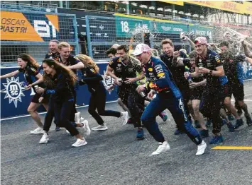  ?? Foto: Hiro Komae, dpa ?? Nass gemacht: Red-Bull-Teammitgli­eder rennen nach einem Gruppenfot­o und bespritzen dabei mit Getränken den Suzuka-Sieger Max Verstappen.