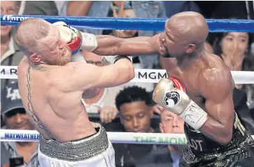  ?? AP ?? Floyd Mayweather Jr hits Conor McGregor during their super welterweig­ht bout in Las Vegas last month.