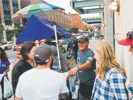  ?? Photos by Daniel Brenner, The Denver Post ?? Joel Watkins, center, sells hot dogs before a Rockies game last week. Six years ago, Watkins had to move from his longtime spot at the northeast corner of 19th and Wynkoop to the southwest corner due to permit issues.