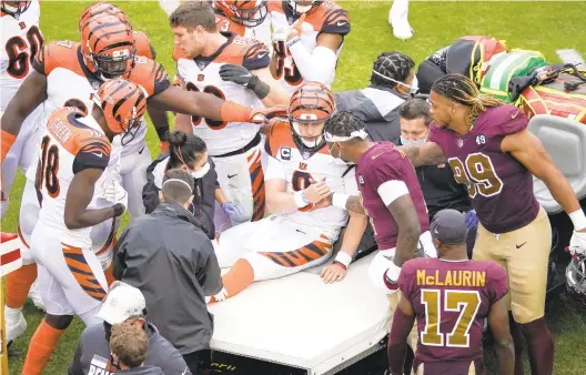  ?? AL DRAGO/ASSOCIATED PRESS ?? Dwayne Haskins shakes hands with injured Cincinnati quarterbac­k Joe Burrow on Sunday during Washington’s 20-9 home victory as receiver Terry McLaurin and defensive end Chase Young (99) look on. All four were Ohio State teammates before Burrow’s transfer to LSU.