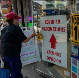  ?? SPENCER PLATT — GETTY IMAGES ?? A pharmacy advertises Covid-19vaccines in a window along Roosevelt Avenue, which passes through the neighborho­ods of Elmhurst, Corona and Jackson Heights, areas that witnessed some of the highest numbers of Covid-19cases and deaths on May 11, 2023, in the Queens borough of New York City.