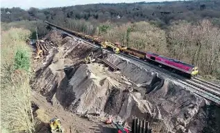  ?? NETWORK RAIL ?? This view from a drone gives some sense of the massive scale of the repairs required before the East Grinstead line could reopen. It shows Freightlin­er’s magenta Class 66 No. 66587 AS ONE, WE CAN in charge of a spoil train on the damaged embankment in March.