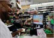  ?? AP PHOTO BY JEFF CHIU ?? Mike Bostic, left, smiles as he is handed a lottery ticket by owner Kewal Sachdev at Ernie’s Liquors in San Jose, Calif., Wednesday, July 25.