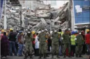  ?? PHOTOS BY REBECCA BLACKWELL — THE ASSOCIATED PRESS ?? Rescue workers and volunteers stand in the middle of the street after an earthquake alarm sounded and a small tremor was felt during rescue operations at the site of a collapsed building in Roma Norte, in Mexico City, Saturday.