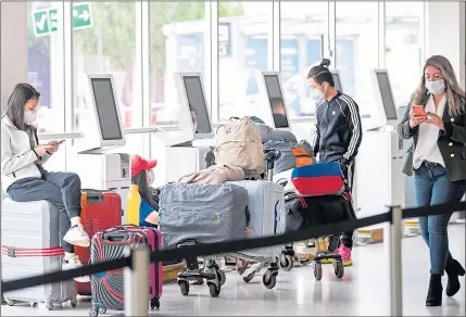  ??  ?? Passengers wearing a protective face masks wait at the check-in area of Edinburgh Airport