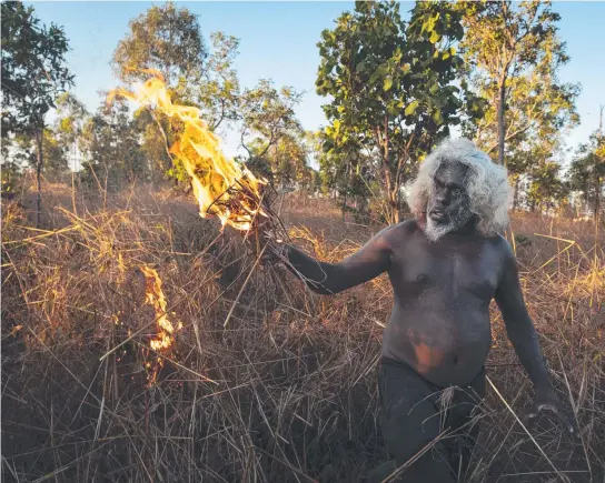  ?? Picture: Matthew Abbott. ?? Nawarddeke­n elder Conrad Maralngurr­a burns grass to rejuvenate the land.