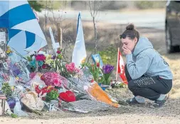  ?? ANDREW VAUGHAN THE CANADIAN PRESS FILE PHOTO ?? A woman pays her respects at a roadside memorial in Portapique, N.S. on April 24, 2020, after 22 people were killed in a murder rampage across the province.