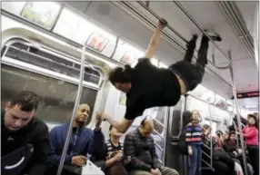  ?? MARK LENNIHAN — THE ASSOCIATED PRESS FILE ?? In this file photo, an acrobatic performer hangs from handrails of a subway car as he entertains riders on the Q train in the Brooklyn borough of New York. If you’re a transporta­tion buff, New York City is the perfect destinatio­n.