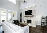  ??  ?? Tall ceilings, a brick fireplace and an abundance of windows add appeal to the living room.