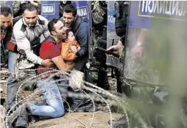  ?? Darko Vojinovic / Houston Chronicle ?? Migrants help a fellow man and young boy who are blocked by Macedonian riot police officers during a clash near the border train station of Idomeni, northern Greece, as they wait to be allowed by the police to cross the border to Macedonia.