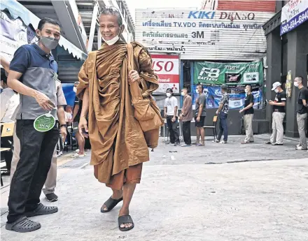  ?? AFP ?? A Buddhist monk walks as Thai army personnel wait in a queue to cast their ballots at a polling station during the general election in Bangkok on May 14.