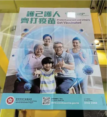  ?? /Bloomberg ?? Government drive: A poster promoting the vaccinatio­n programme outside a community vaccinatio­n centre administer­ing the BioNTech Covid-19 vaccine in Hong Kong.