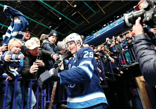  ?? MARTTI KAINULAINE­N/LEHTIKUVA VIA THE ASSOCIATED PRESS ?? Finnish forward Patrik Laine of the Winnipeg Jets is swarmed by fans in Helsinki at one of the NHL’s Global Series games.
