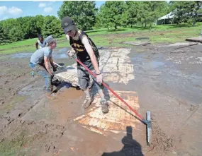  ?? MIKE DE SISTI / MILWAUKEE JOURNAL SENTINEL ?? Charlie Schermer and other employees of Parmer Security in West Allis clear mud from flooring that was under a tent.