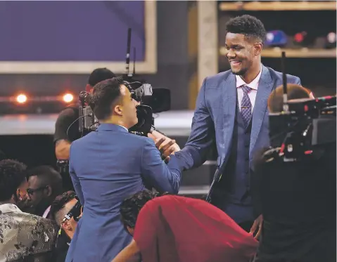  ?? KEVIN HAGEN/ASSOCIATED PRESS ?? Arizona’s Deandre Ayton, right, is congratula­ted by friends and family after he was picked first overall by the Phoenix Suns during the NBA draft Thursday in New York.